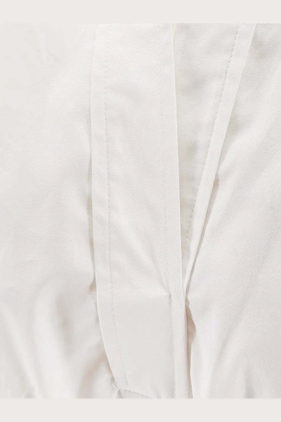 White cotton fabric with neat straight stitching on seams of nude women’s polo cotton dress white