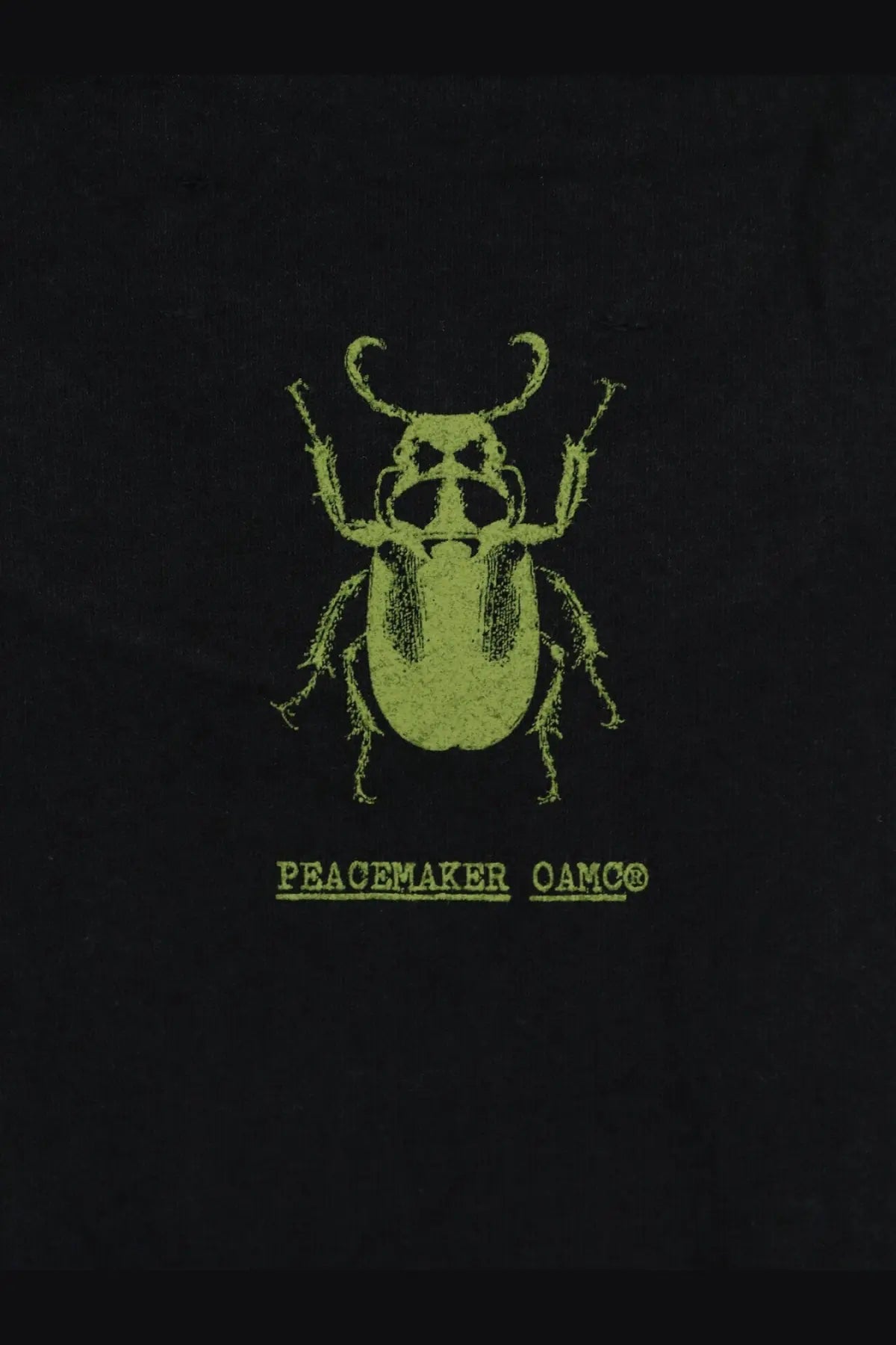 Black cotton oamc peacemaker men’s t-shirt with lime green stylized beetle graphic and logo text below