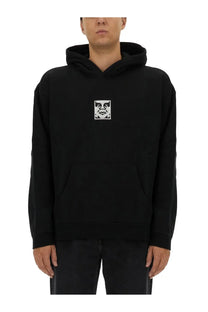 Obey men’s black hoodie featuring a white eye and mouth graphic on the chest in comfortable cotton material