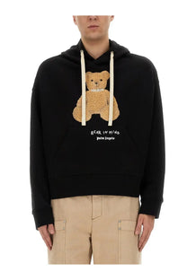 Palm Angels men’s black hoodie with tan teddy bear appliqué wearing a pearl necklace and embroidered text on front