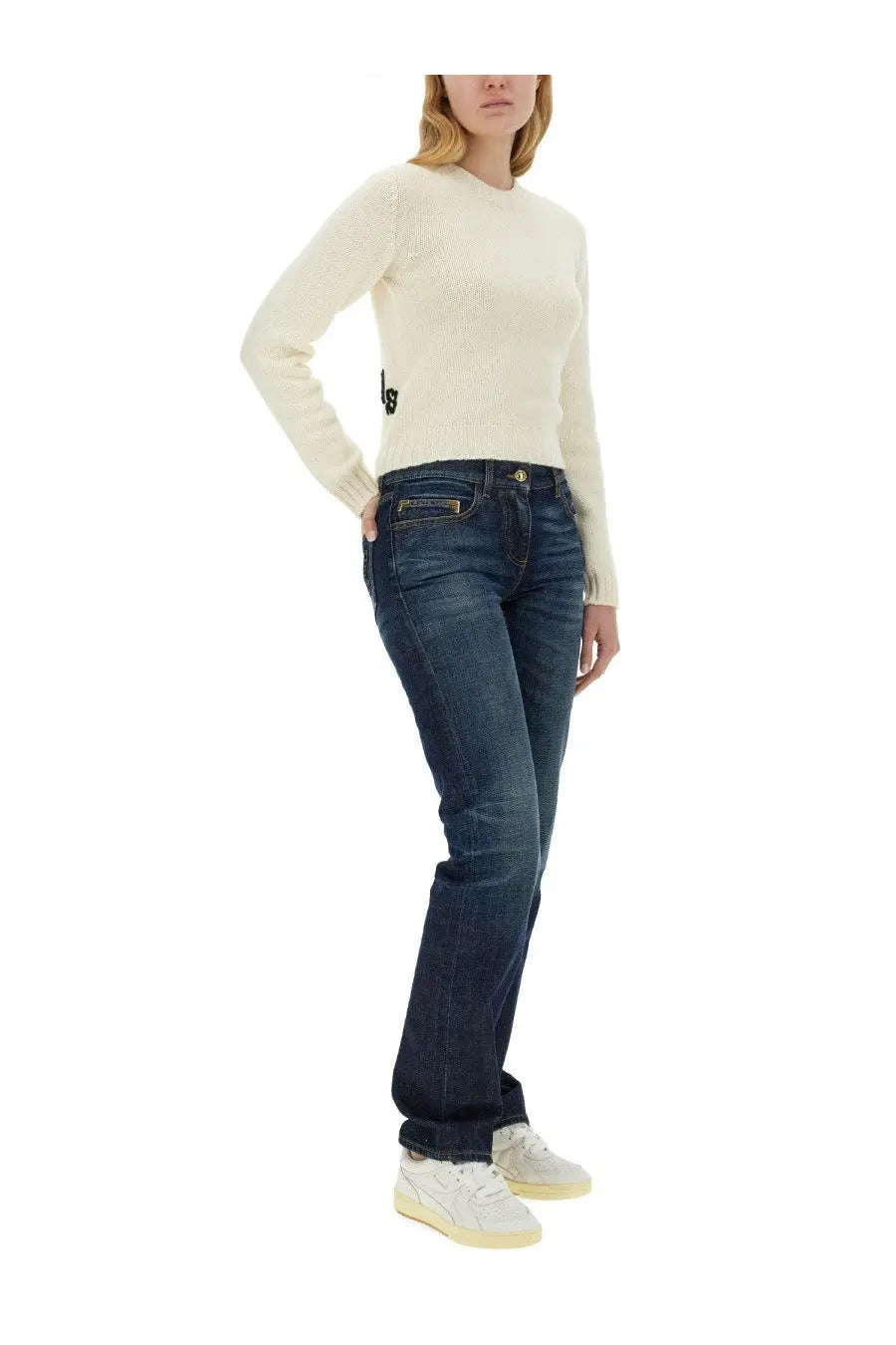 Cream-colored ribbed knit sweater with small black logo on left side seam paired with palm angels women’s blue straight leg jeans