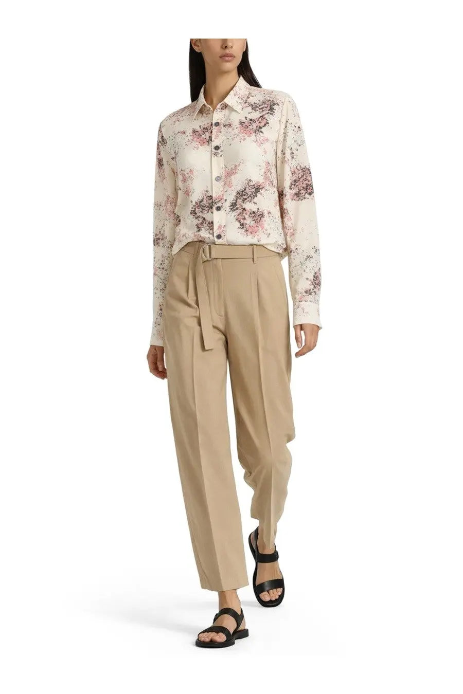 A woman wearing a long-sleeved floral button-down blouse with Paul Smith women’s belted beige pants