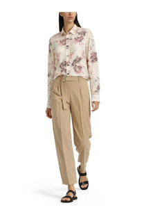 A woman wearing a long-sleeved floral button-down blouse with Paul Smith women’s belted beige pants