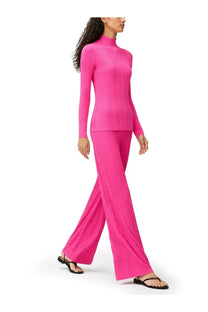A vibrant fuchsia ribbed knit turtleneck top paired with matching wide-leg pants in pleats please issey miyake style