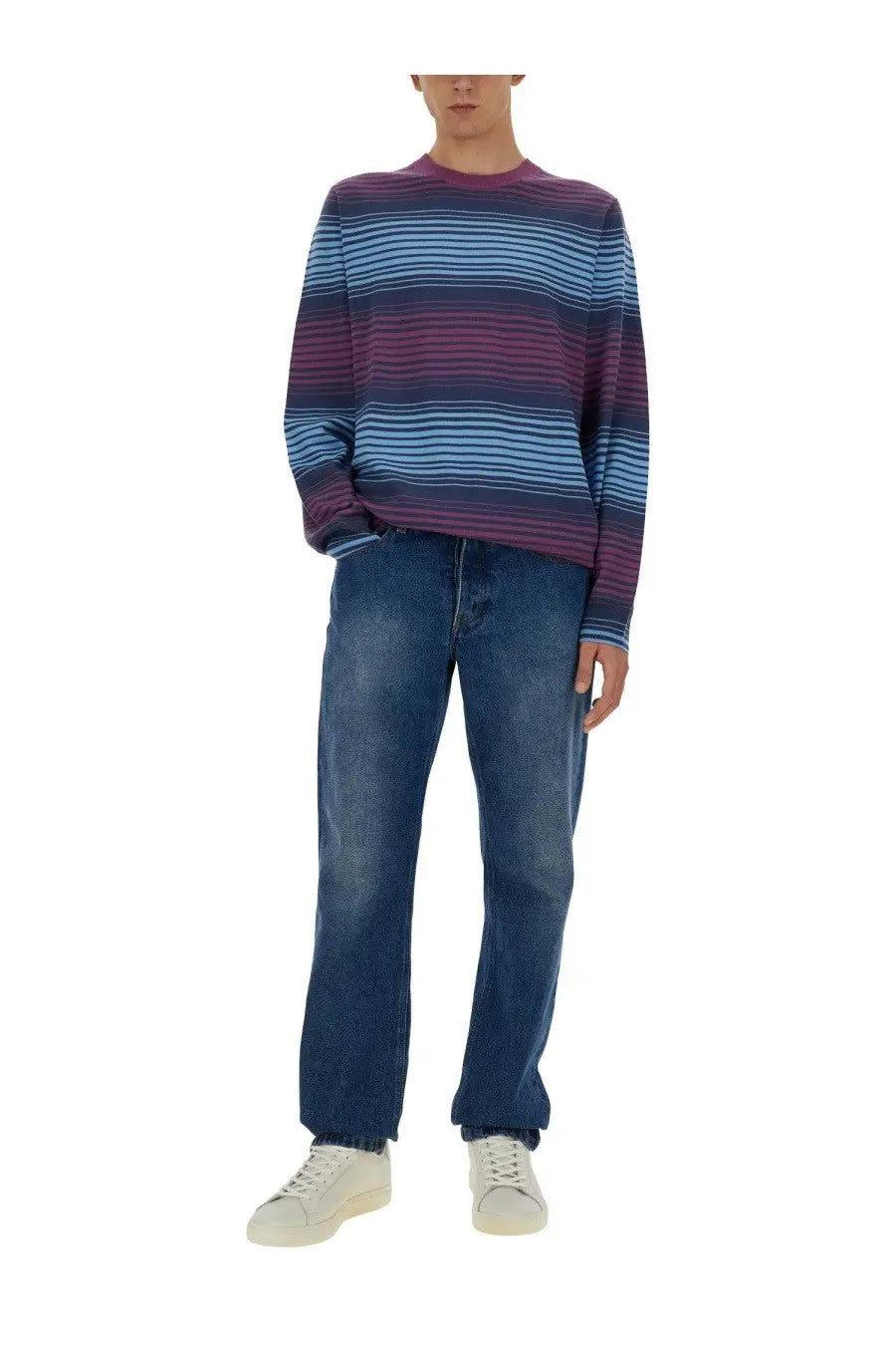 A man wearing a ps by paul smith men’s multicolor striped long-sleeved sweater with purple and light blue bands paired with dark wash jeans
