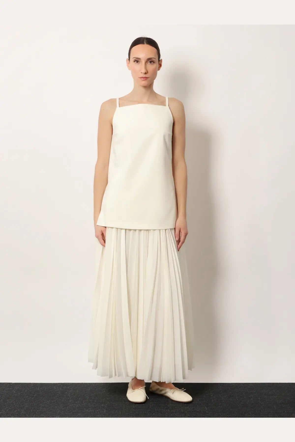 A minimalist off-white sleeveless top with thin straps and a square neckline paired with r2w women’s aristo pleated skirt white