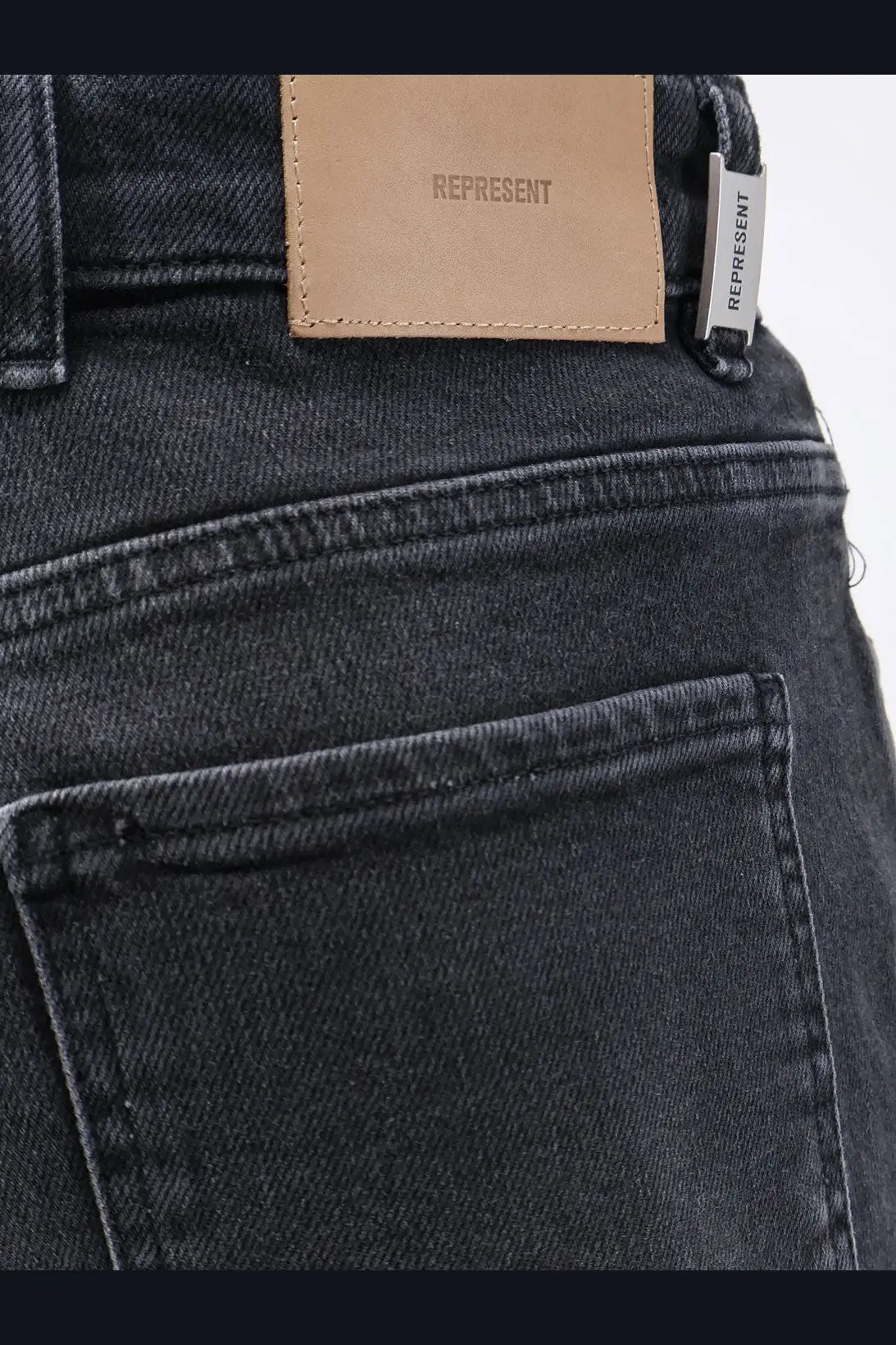 Dark-wash denim represent men’s boot cut jeans black showing tan leather brand patch and silver embroidered tag on back