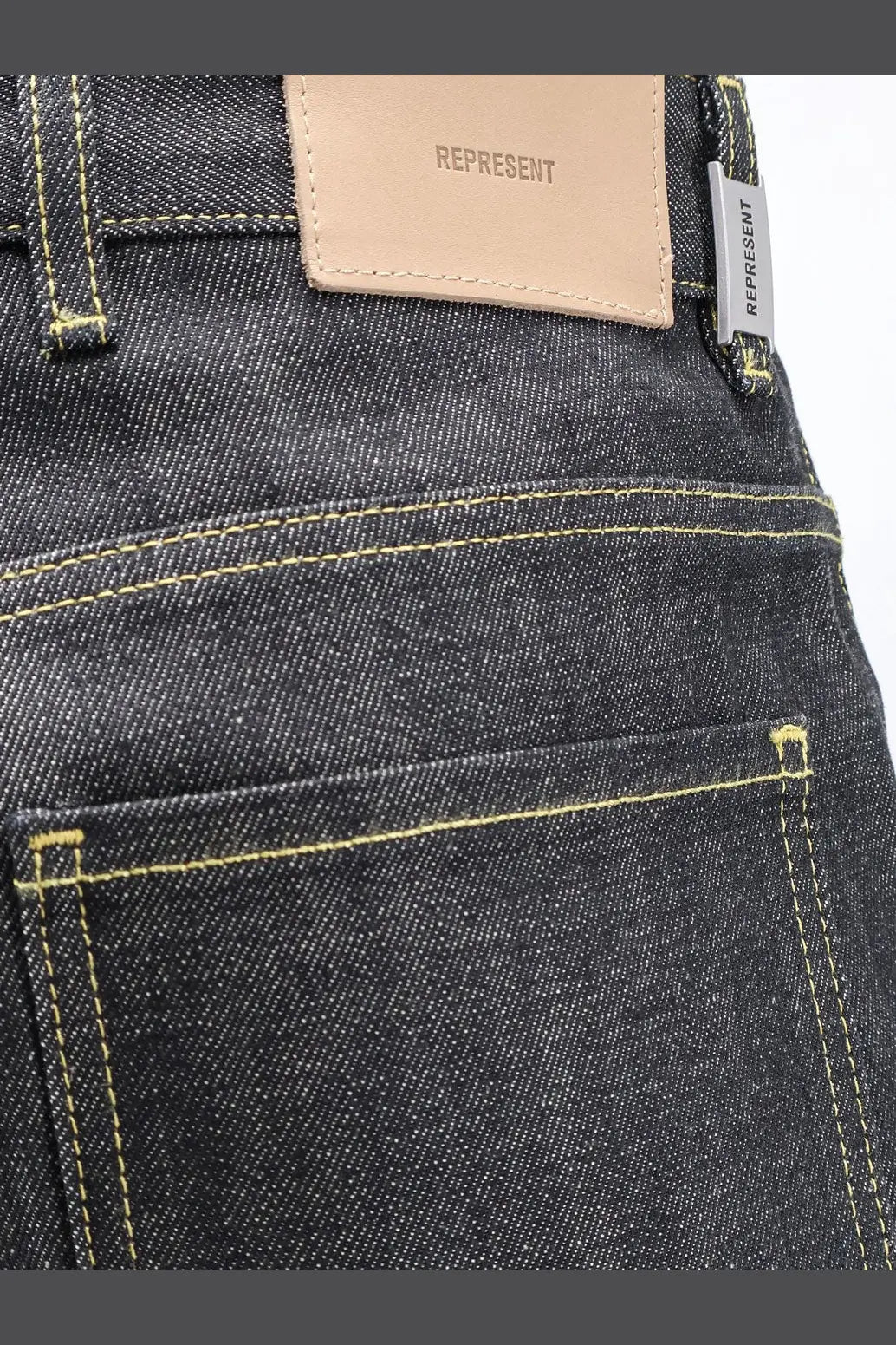 Dark-wash denim jeans with contrasting yellow stitching and beige leather patch for represent men’s selvedge denim shirt black