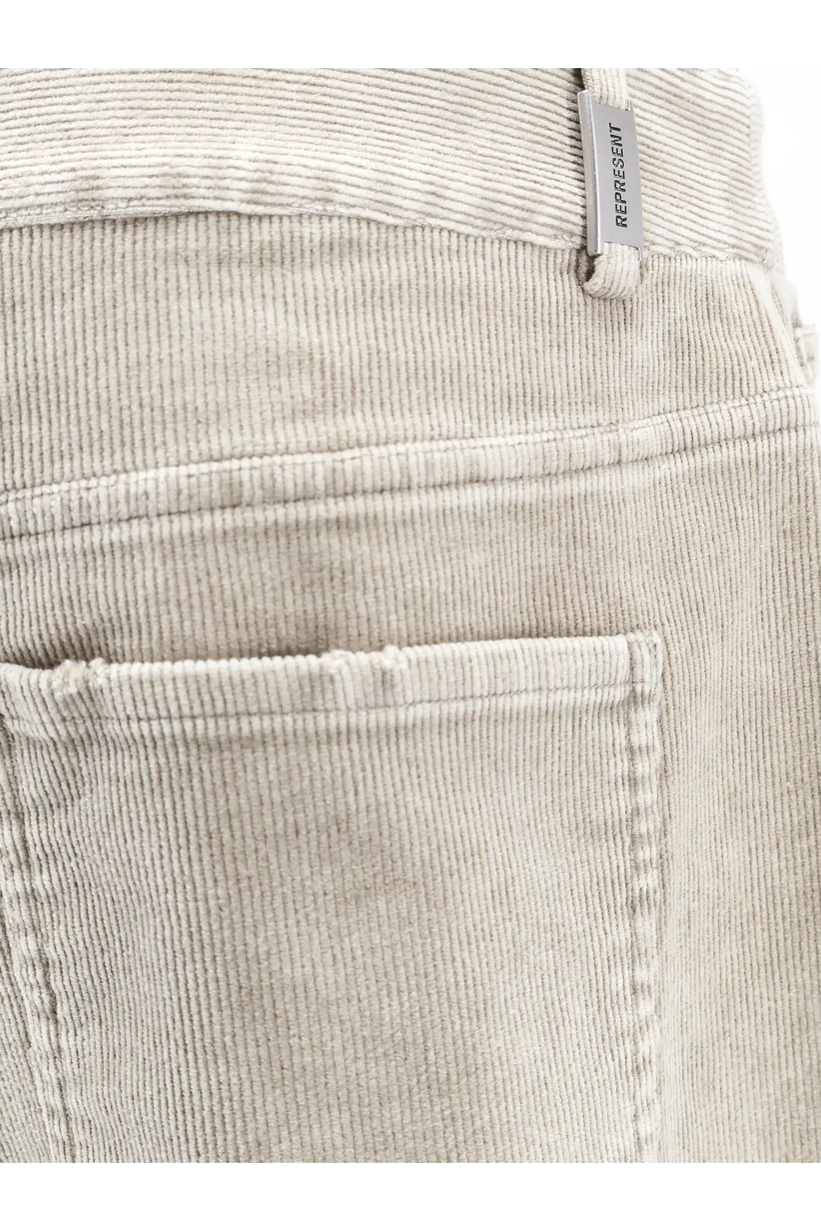 Beige corduroy pants with subtle ribbed texture and represent branded tag at waistband for men