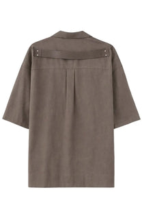 Back view of a taupe-colored rick owens men’s magnum tommy short sleeve shirt with structured collar and horizontal strap detail