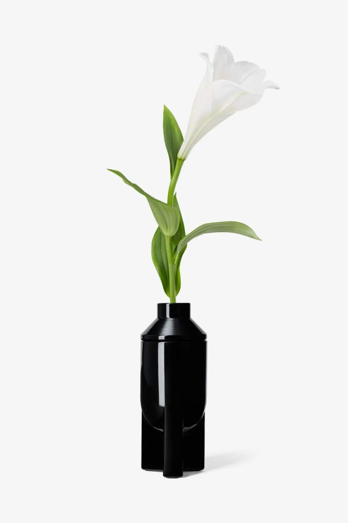 A sleek black ceramic vase with a modern geometric design holding a white lily for rick owens unisex galss scented candle lapparition black
