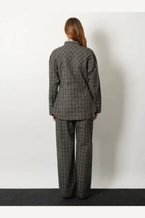 A woman wears rohe women’s black cotton shirt in black and white plaid matching oversized button-up and wide-leg trousers