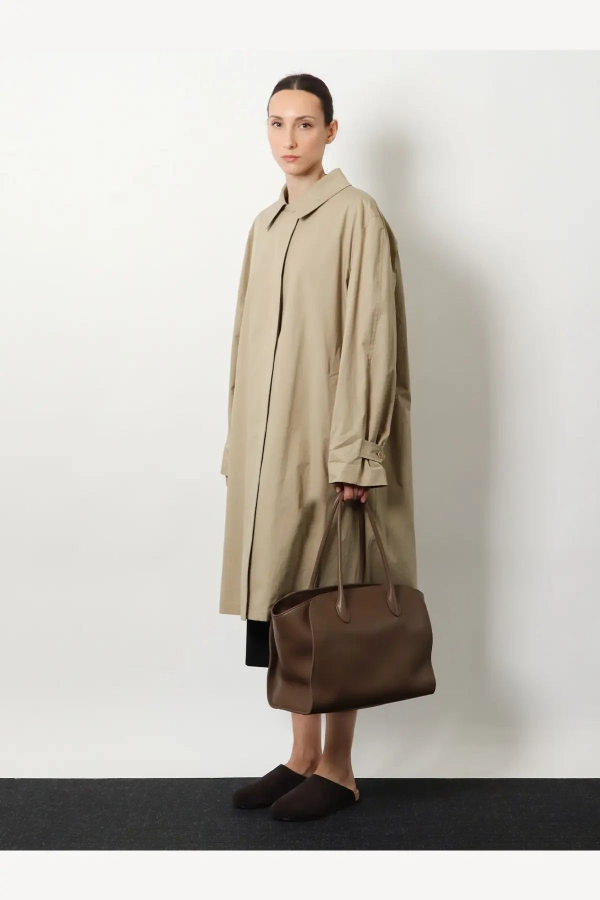 Beige trench coat with classic collar and long sleeves paired with the row women’s marlo brown leather shoulder bag