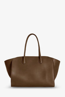 The row women’s marlo leather shoulder bag brown is a sleek medium brown leather tote with curved handles and a minimalist design