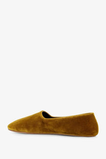 A mustard-yellow suede slip-on flat shoe with a sleek minimalist design called The Row women’s Ponti velvet loafers yellow