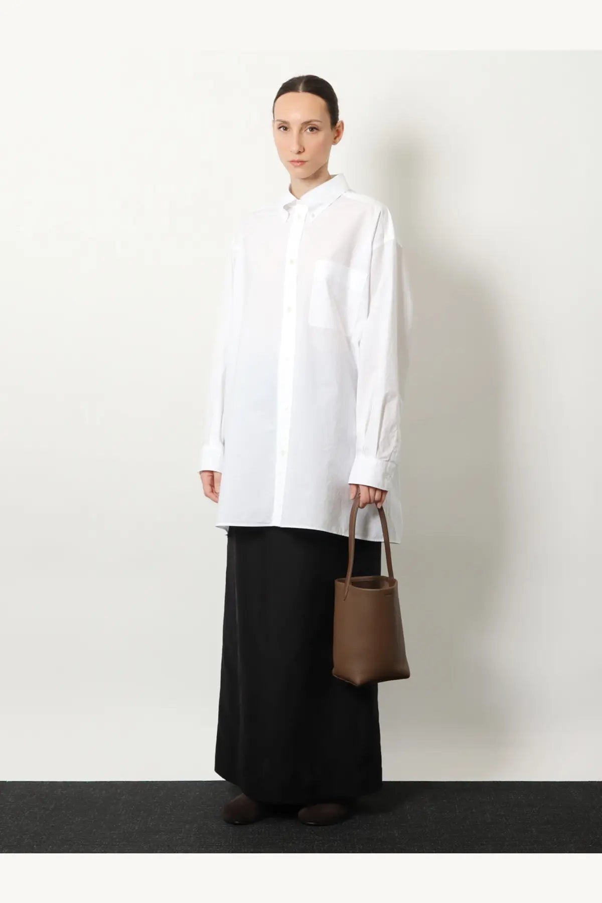 Brown leather bucket bag paired with The Row women’s saul cotton and silk long skirt in black