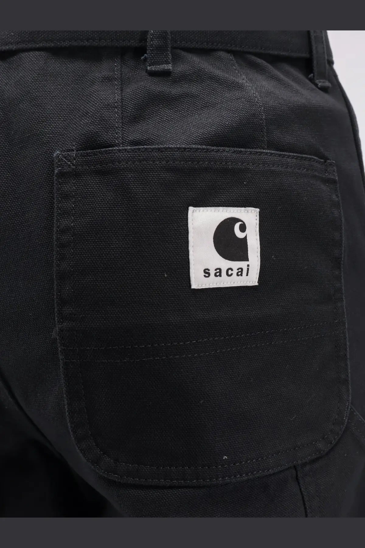 Black sacai men’s Carhartt Wip duck cotton trousers featuring durable canvas fabric and a white patch with black C logo