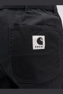 Black sacai men’s Carhartt Wip duck cotton trousers featuring durable canvas fabric and a white patch with black C logo
