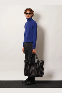 Black leather tote bag with structured handles and minimalist design paired with saint laurent mens blue cashmere turtleneck