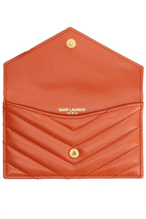 A coral-colored Saint Laurent Paris quilted chevron card holder with gold-tone hardware in Cassandras red