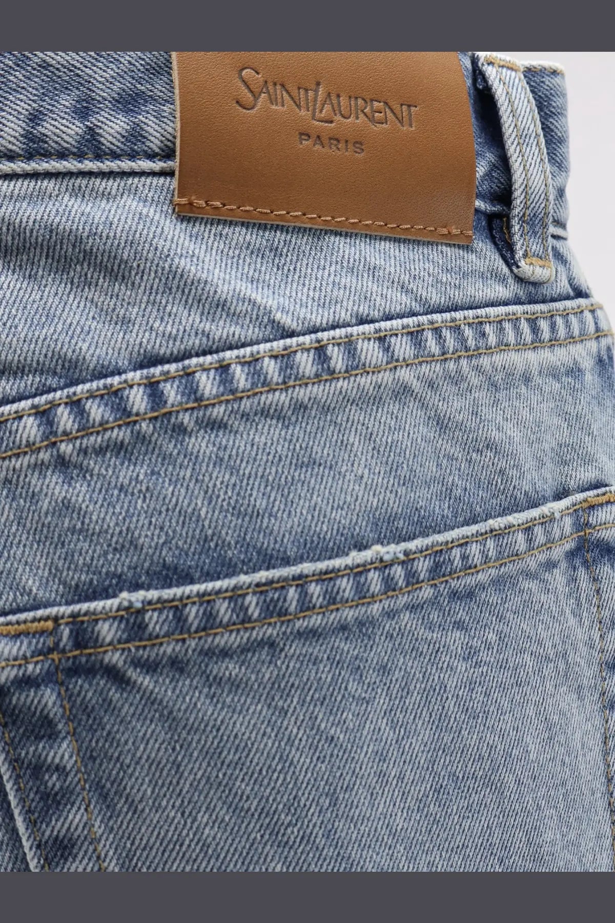 Light-wash denim saint laurent women’s relaxed straight jeans with brown leather brand label on the waistband back side