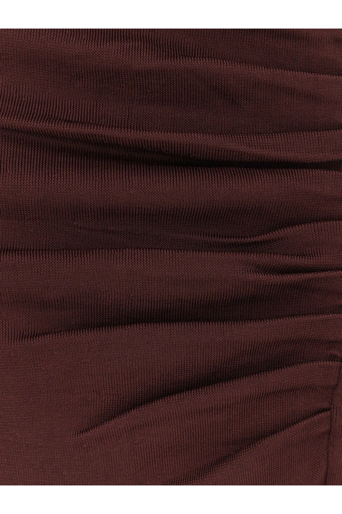 A close-up of a dark burgundy ribbed knit fabric with subtle horizontal ruching on a self-portrait draped dress