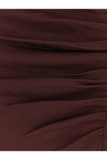 A close-up of a dark burgundy ribbed knit fabric with subtle horizontal ruching on a self-portrait draped dress