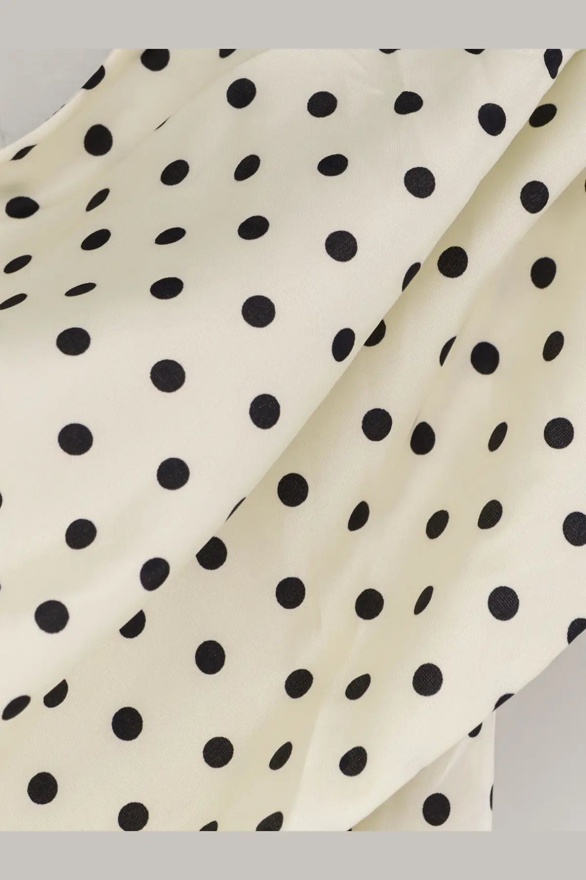 Cream-colored satin mini dress by self-portrait with evenly spaced black polka dots and a smooth fabric texture