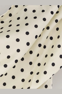Cream-colored satin mini dress by self-portrait with evenly spaced black polka dots and a smooth fabric texture