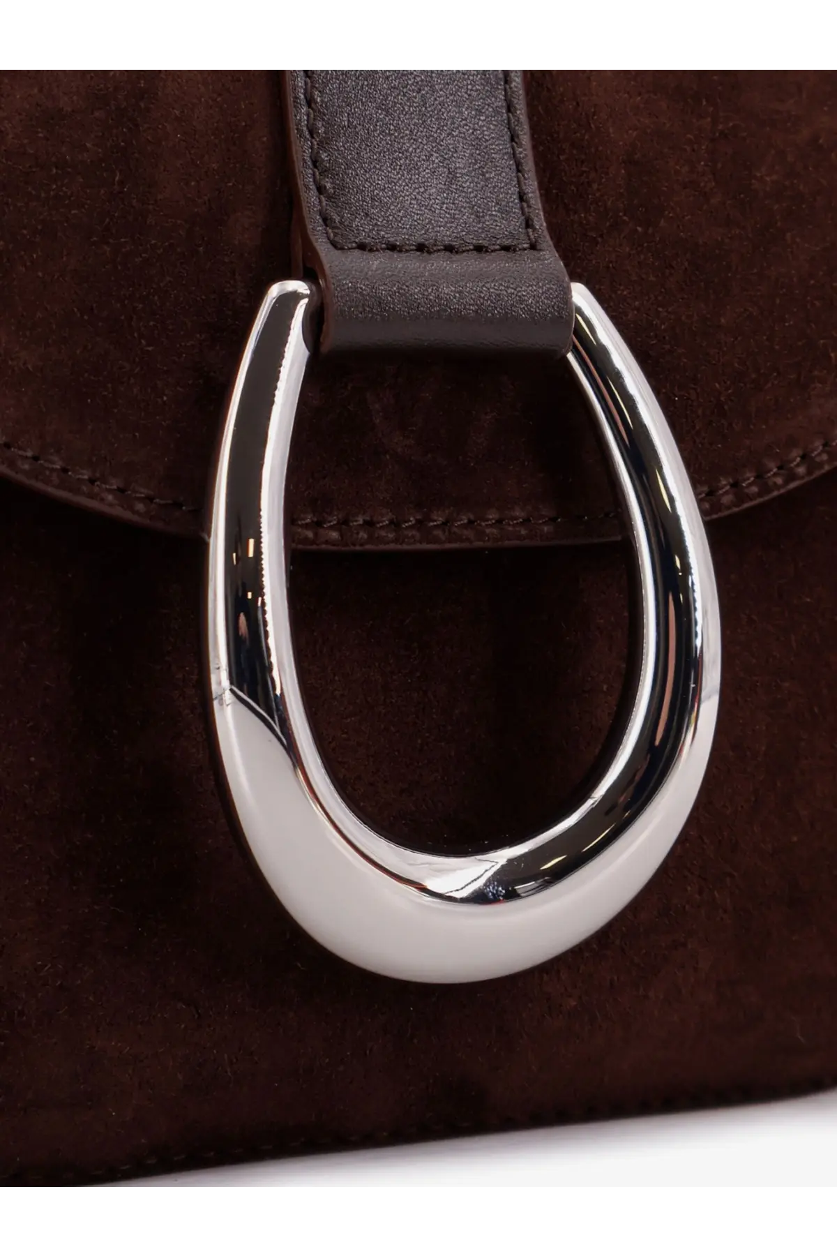 A sleek silver horsebit clasp on a brown suede Staud womens Bella saddle crossbody bag