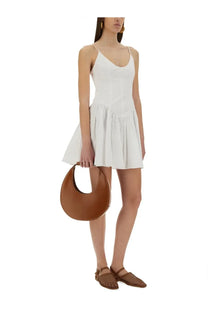 Brown leather crescent-shaped handbag paired with Staud women’s mini dress Dena white for versatile style
