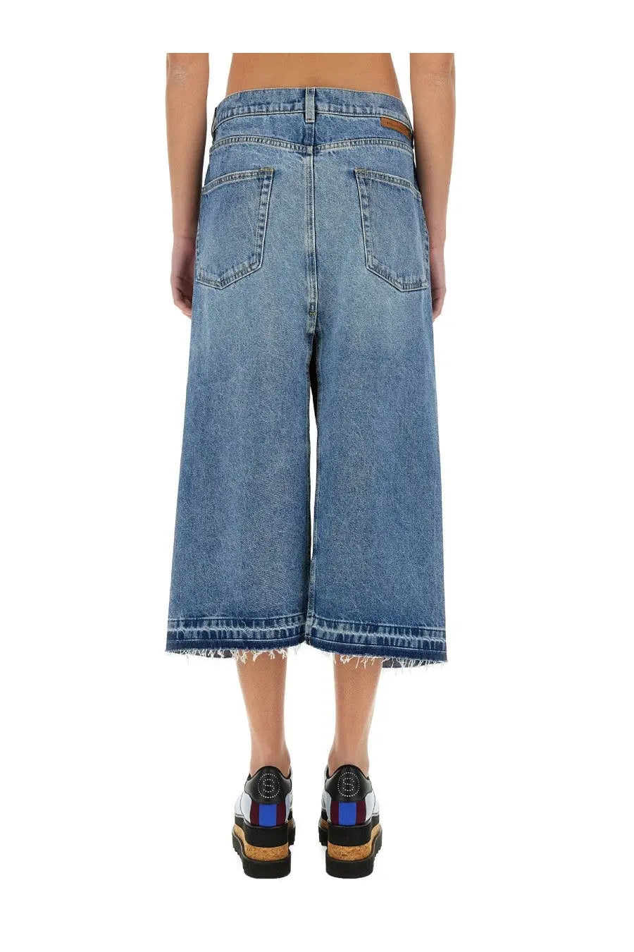 Blue denim culottes with frayed hem and classic back pockets shown from the back by Stella McCartney