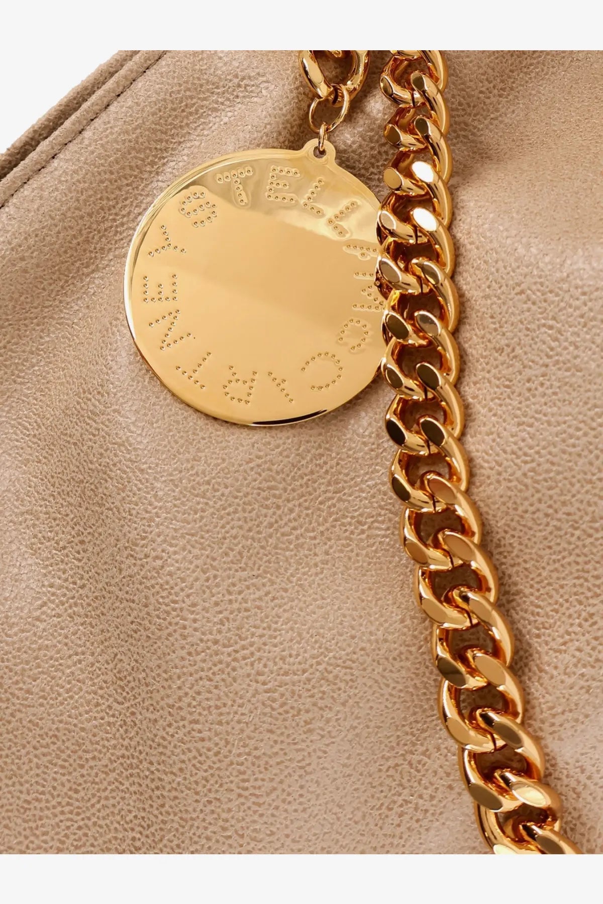 Gold-tone circular pendant embossed stella mccartney lettering attached to gold-tone chain on white falabella bag