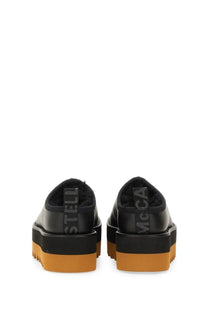 Back view of black leather stella mccartney women’s sneak elyse platform slip-ons with orange rubber sole