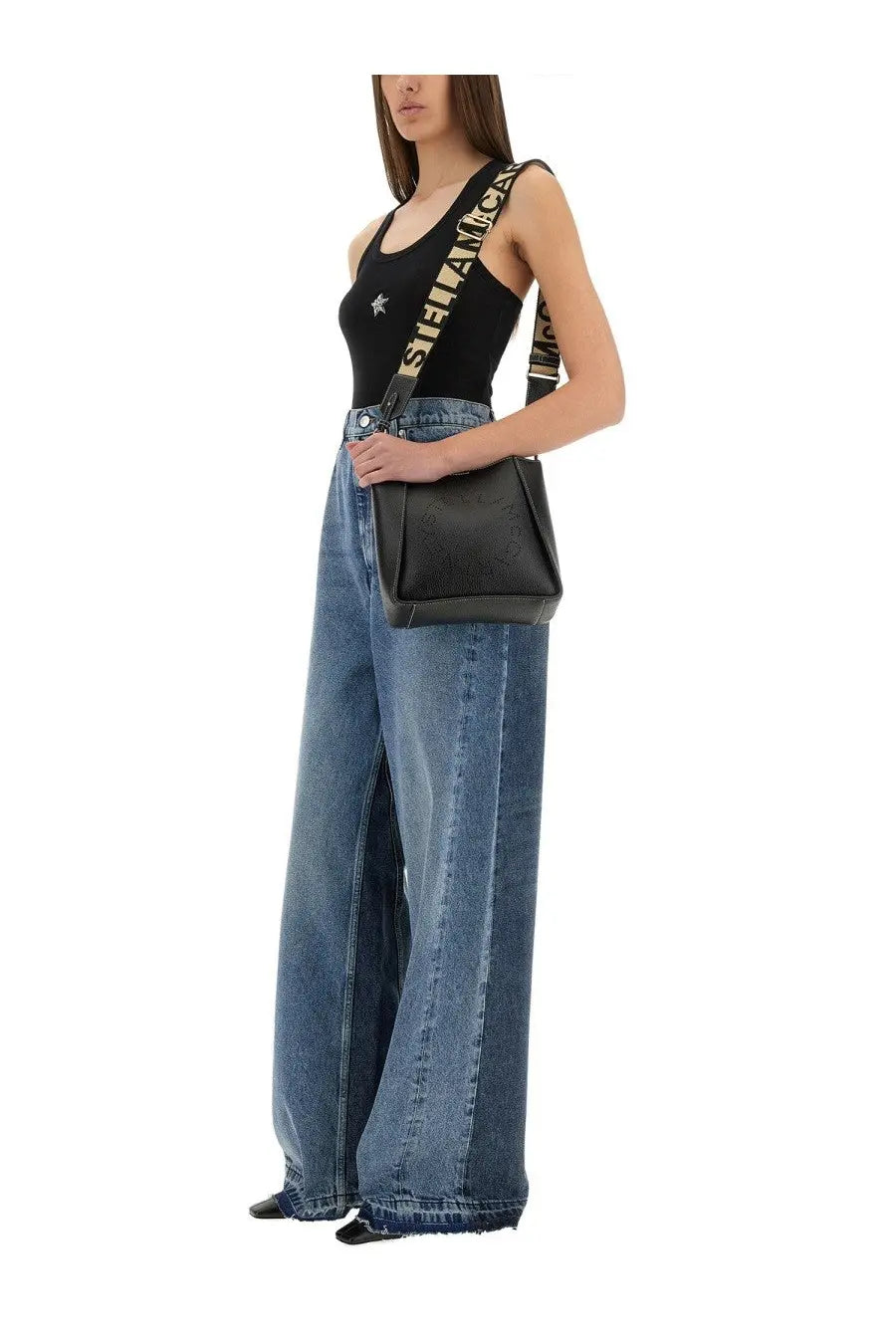 Black leather crossbody bag with bold repeating stella mccartney logo strap in white and black with wide leg blue jeans