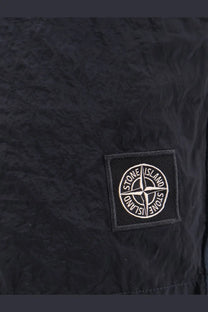 Black stone island patch with white embroidered logo on textured fabric on stone island men’s econylon swim trunks blue
