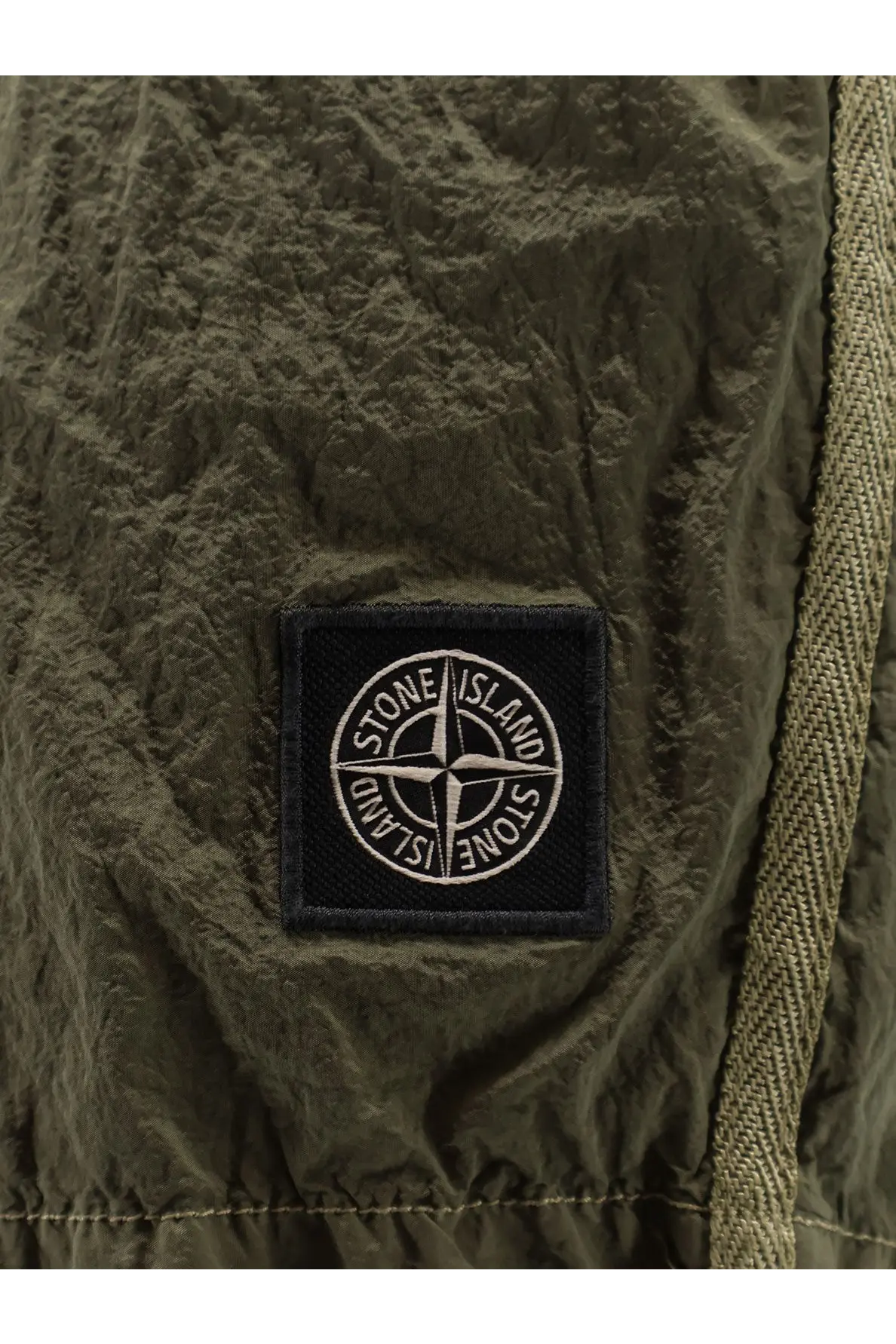 Olive green textured fabric patch with black embroidered stone island compass logo on mens econylon swim trunks