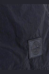 Black stone island embroidered logo patch on dark fabric of stone island men’s blue nylon swim trunks