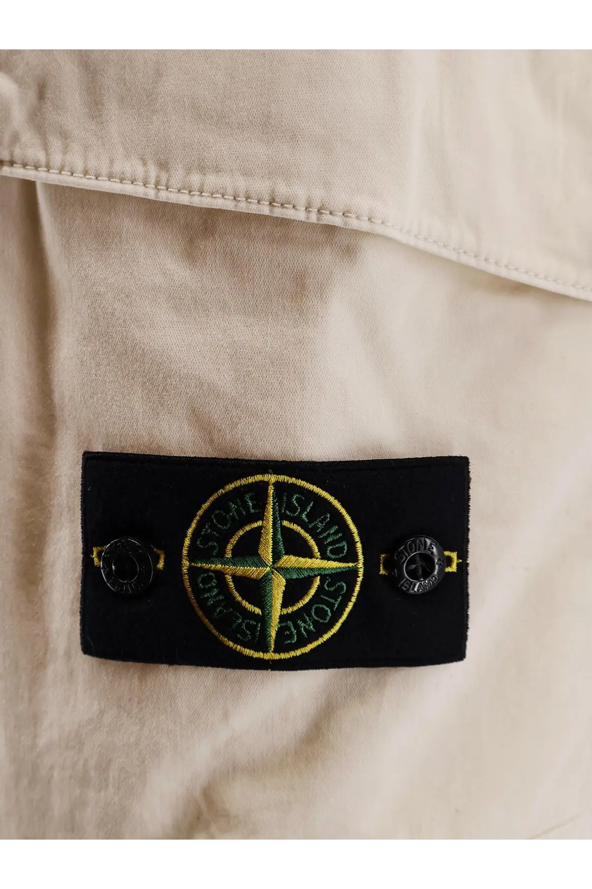 Black rectangular label with yellow and green stone island compass rose logo on Stone Island organic cotton white bermuda shorts