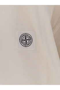 White stone island patch with black embroidered compass rose on light fabric of stone island men’s organic cotton shirt
