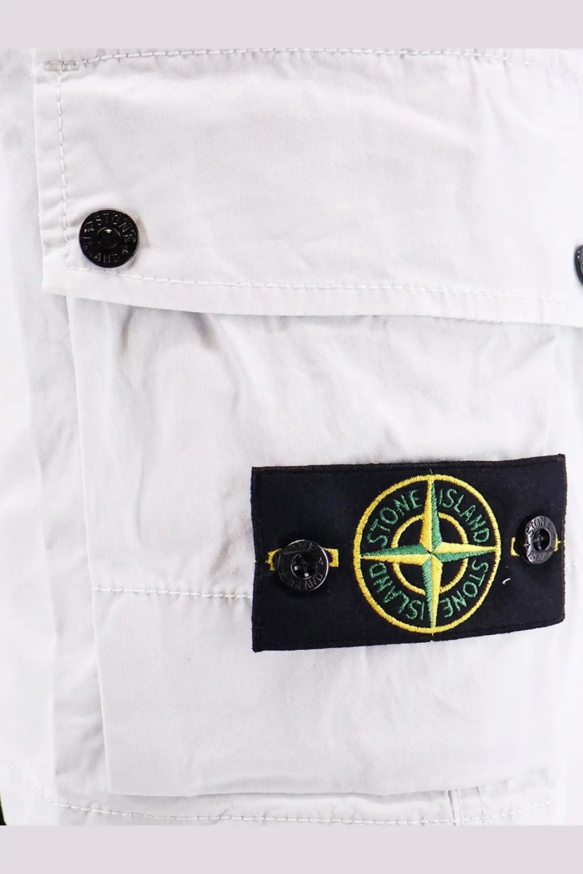 Stone Island men’s organic cotton blue shorts with white stone island cargo pants featuring a black patch with green yellow compass rose logo