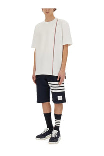 Thom browne men’s white jersey shirt with short sleeves featuring a red white and blue vertical stripe down the side