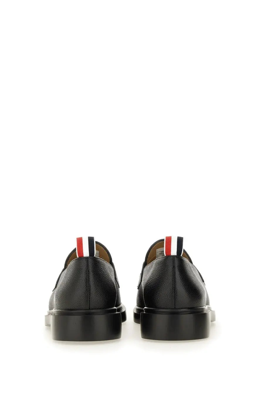 Black leather Thom Browne men’s moccasin penny loafer showing back with red white and blue striped tab heel