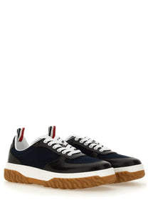 Thom Browne men’s trainer letterman blue navy and black low-top sneakers with white laces and gum rubber sole visible from back