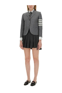 Thom Browne women’s single breasted grey blazer with three white sleeve stripes worn over collared shirt and tie