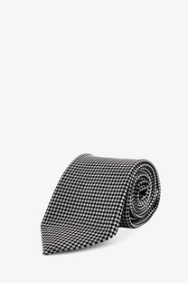 A sleek black and white houndstooth patterned Tom Ford men’s silk tie rolled neatly for display