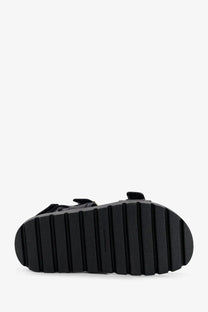 Black rubber sole with vertical ridges on the back side of tory burch women’s mellow leather sandals black