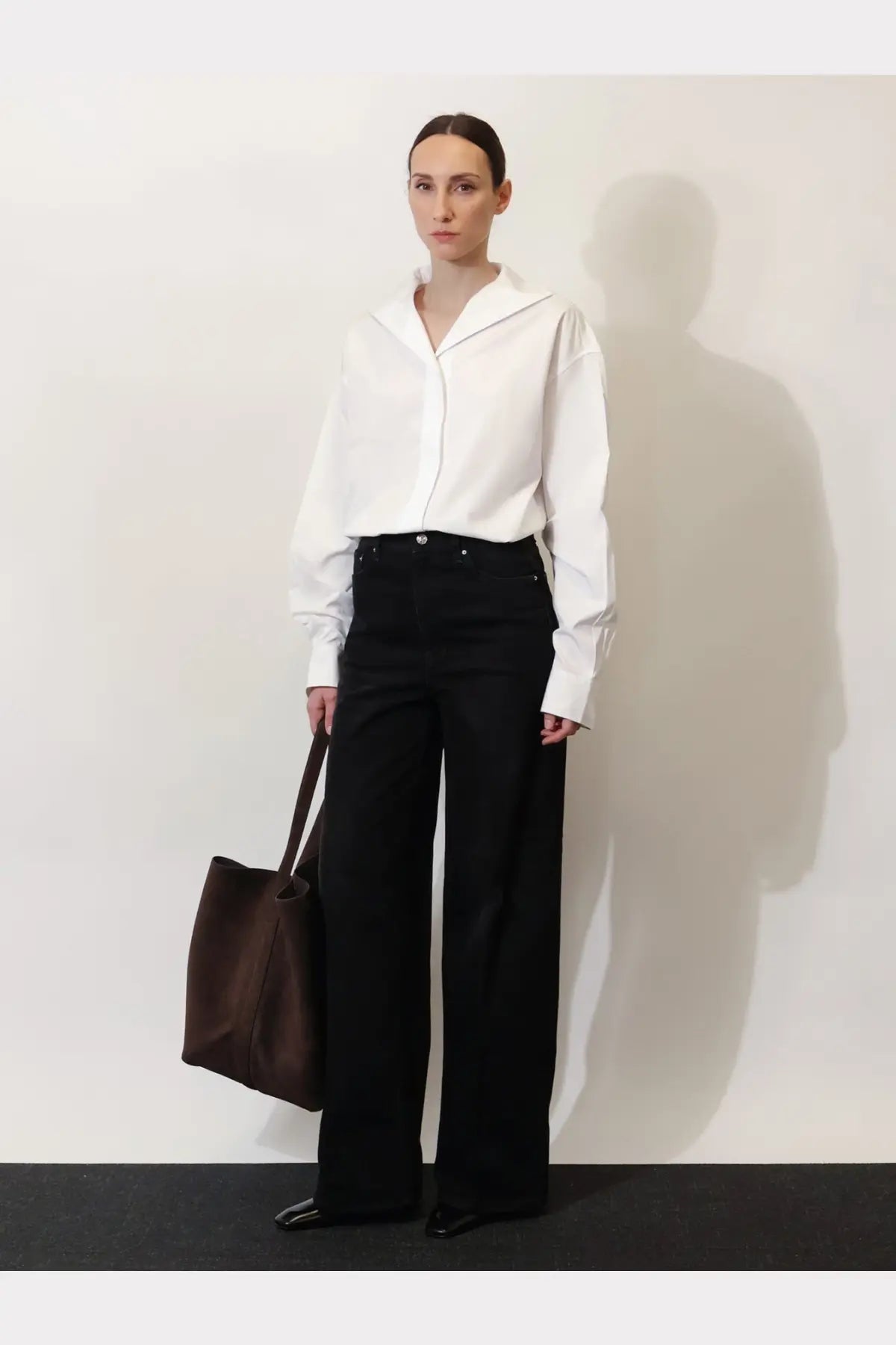 White oversized collar shirt with long sleeves and minimalist design paired with toteme women’s black denim jeans black