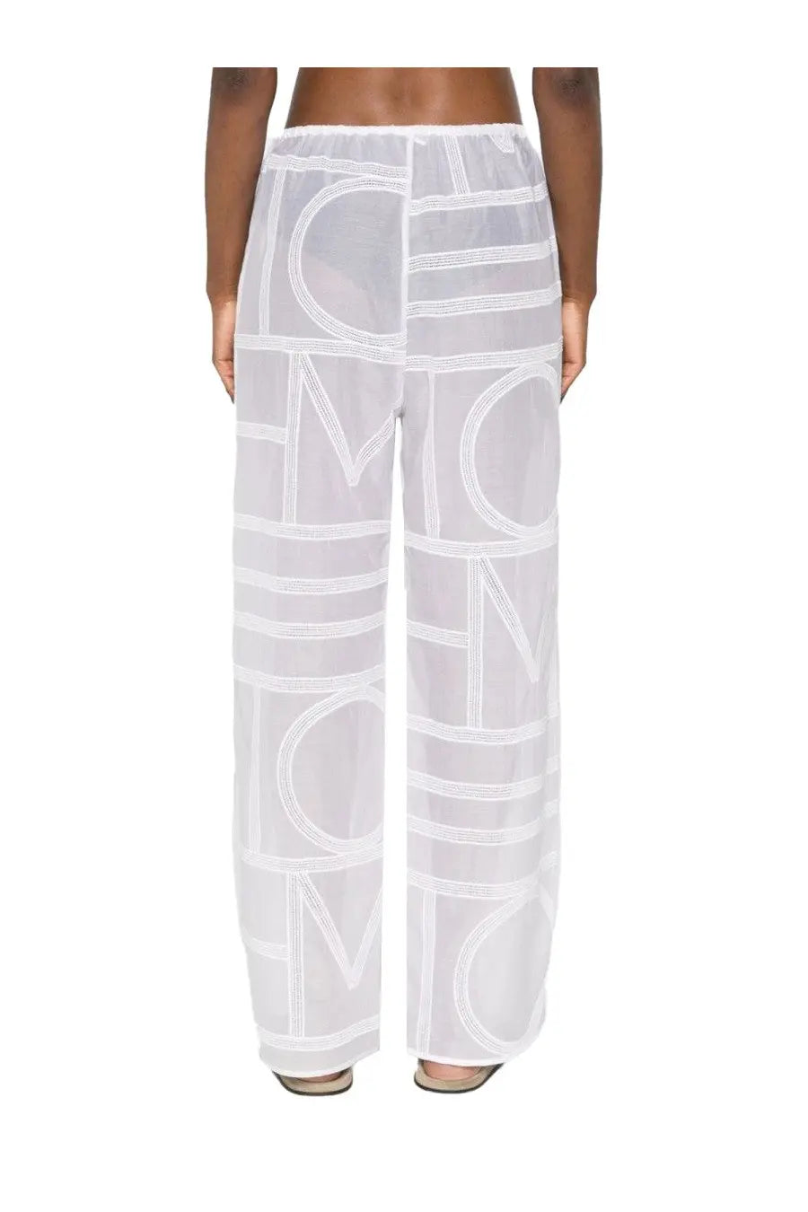 White sheer wide-leg cotton and silk pants by Toteme featuring bold geometric logo print in contrasting white thread