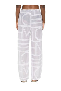 White sheer wide-leg cotton and silk pants by Toteme featuring bold geometric logo print in contrasting white thread
